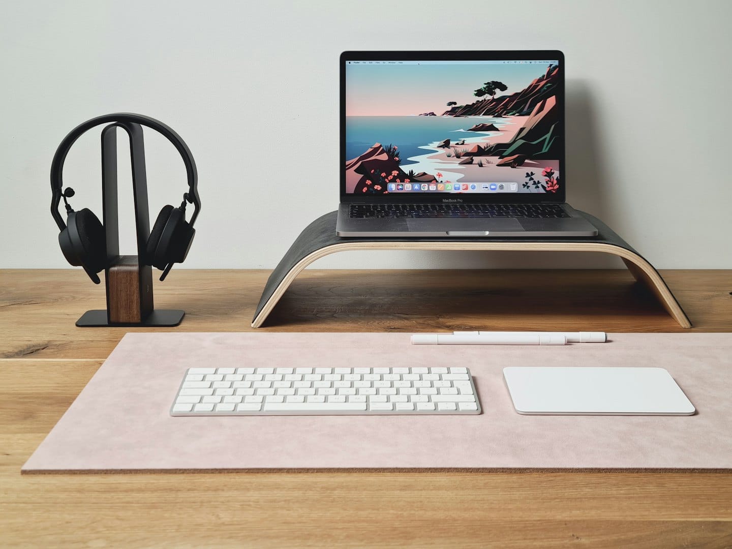 Laptop, headphones, keyboard, and trackpad on a desk.